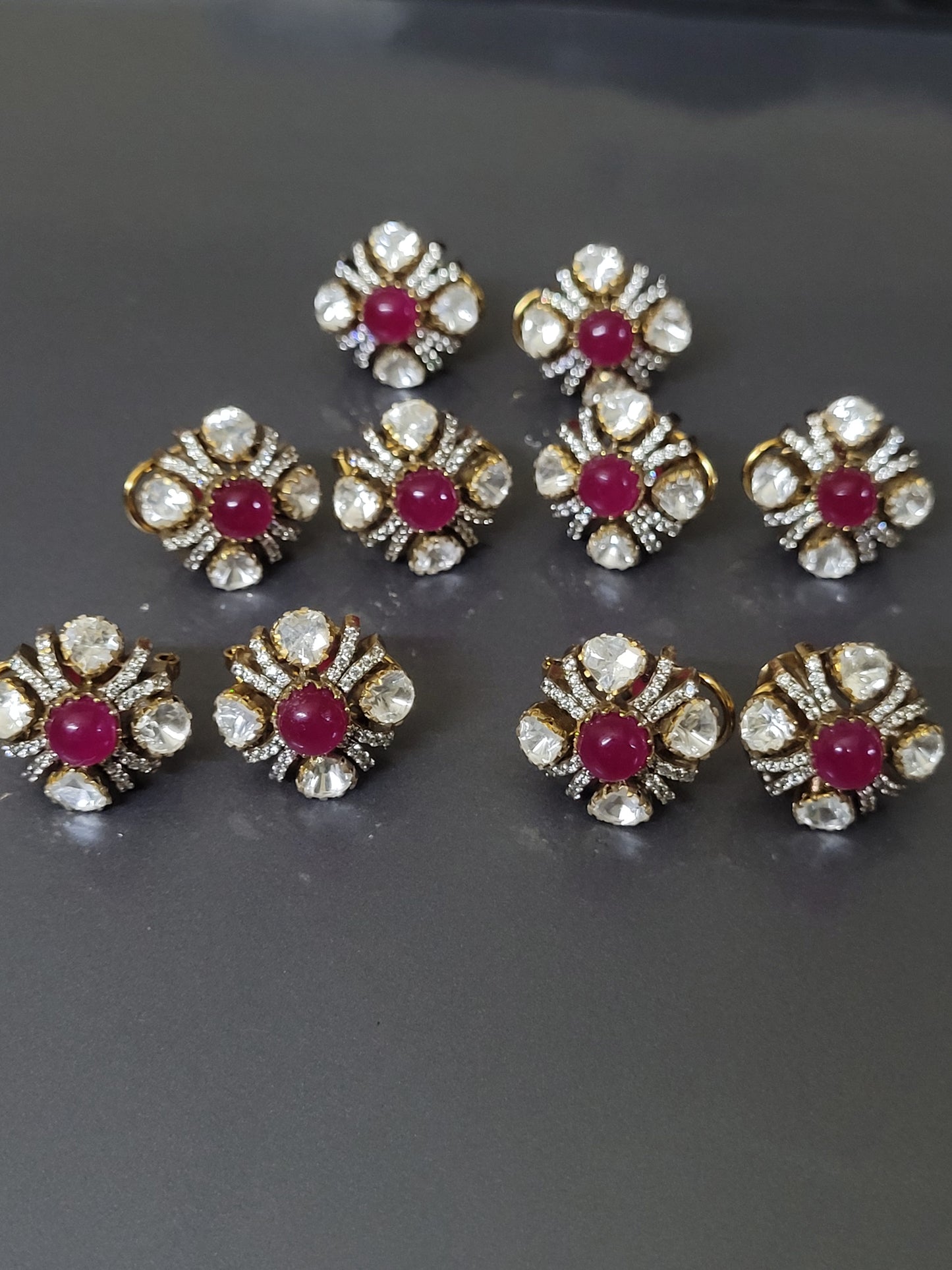 Gold and diamond earrings with red gemstones on a gray background