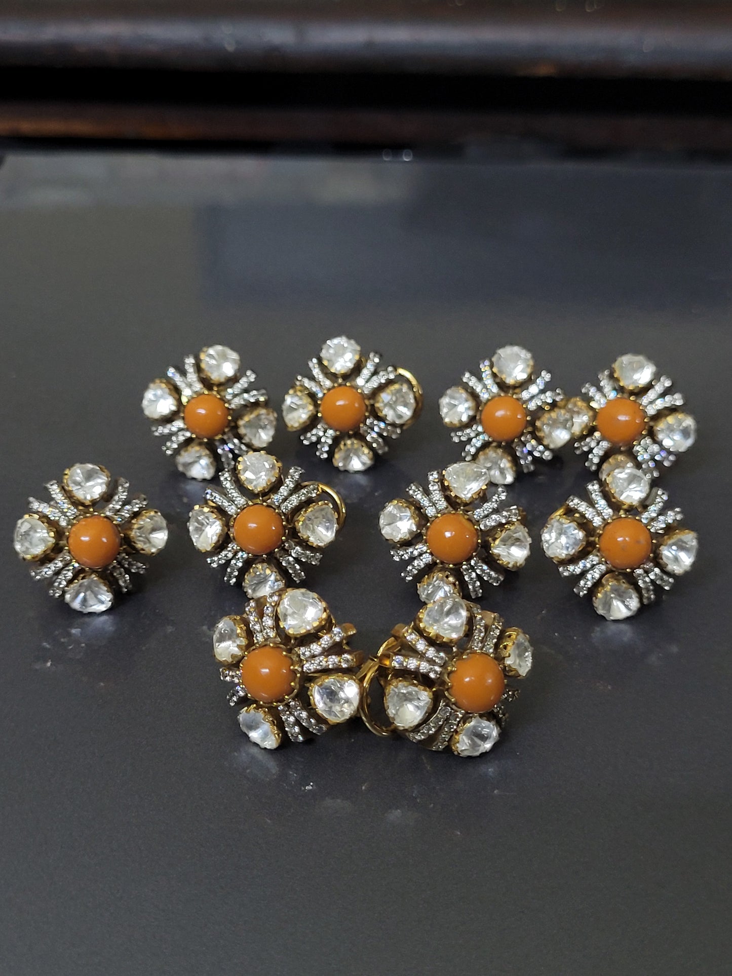 Gold and diamond earrings with red gemstones on a gray background