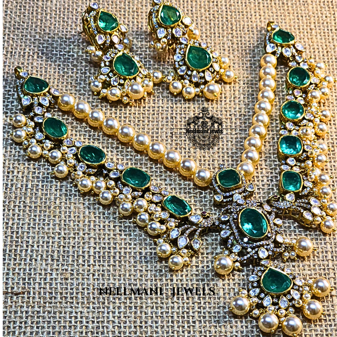 Jewelry set with green stones and gold accents on a textured fabric background