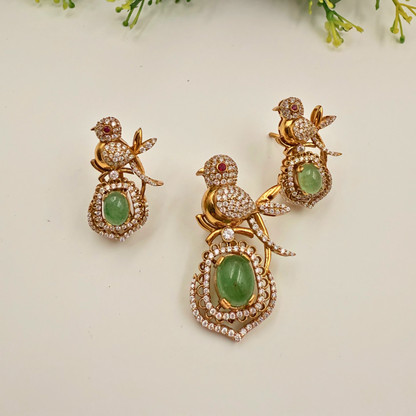 Gold bird-shaped earrings with green gemstones on a light background