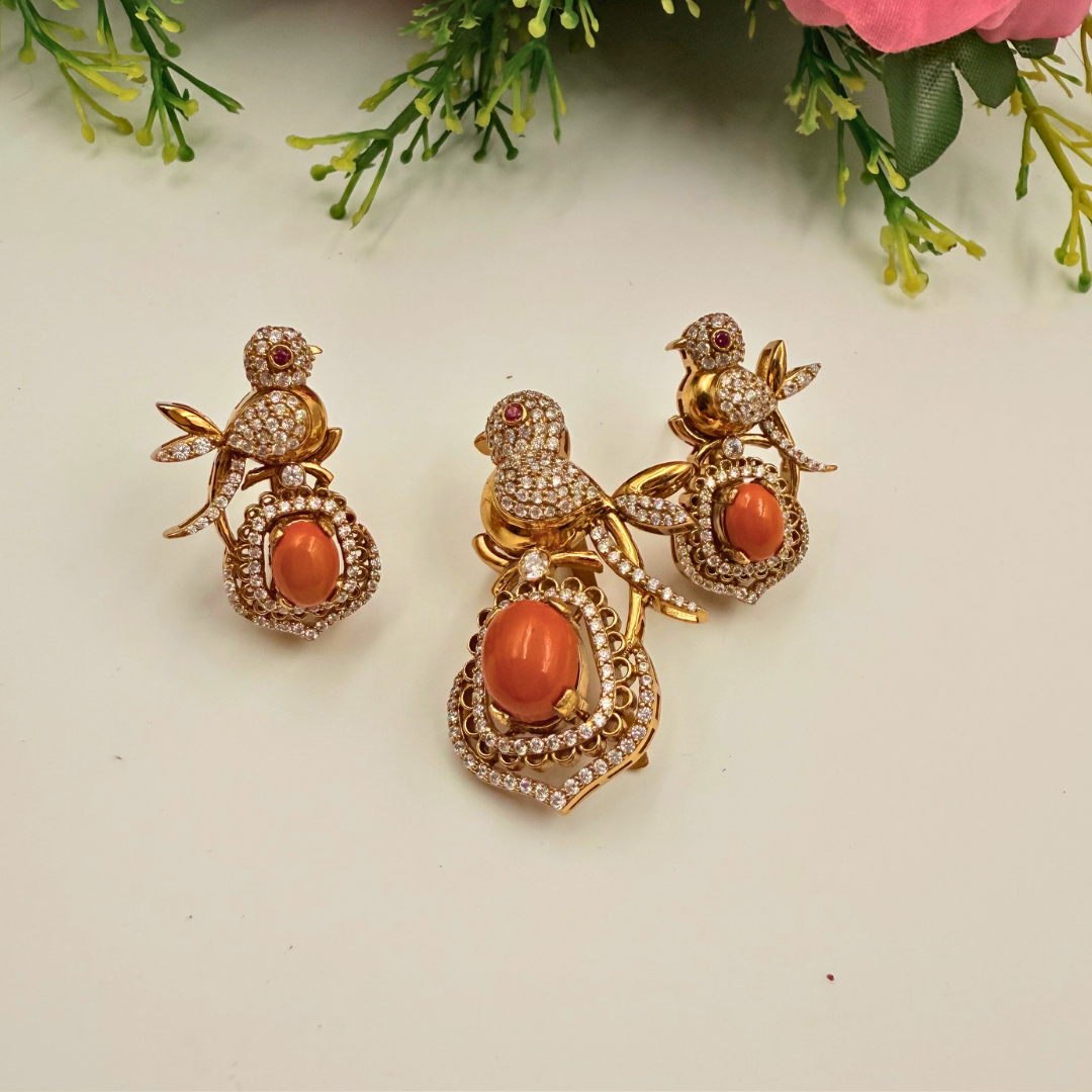 Pair of ornate earrings with coral-like stones on a light background