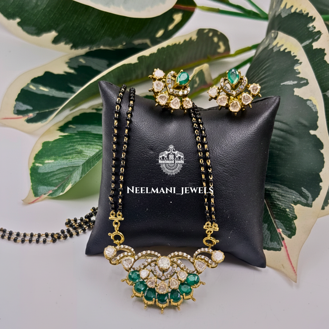 Neelmani Jewels mangal sutra   and earring on a black jewelry pillow with leaves in the background   
